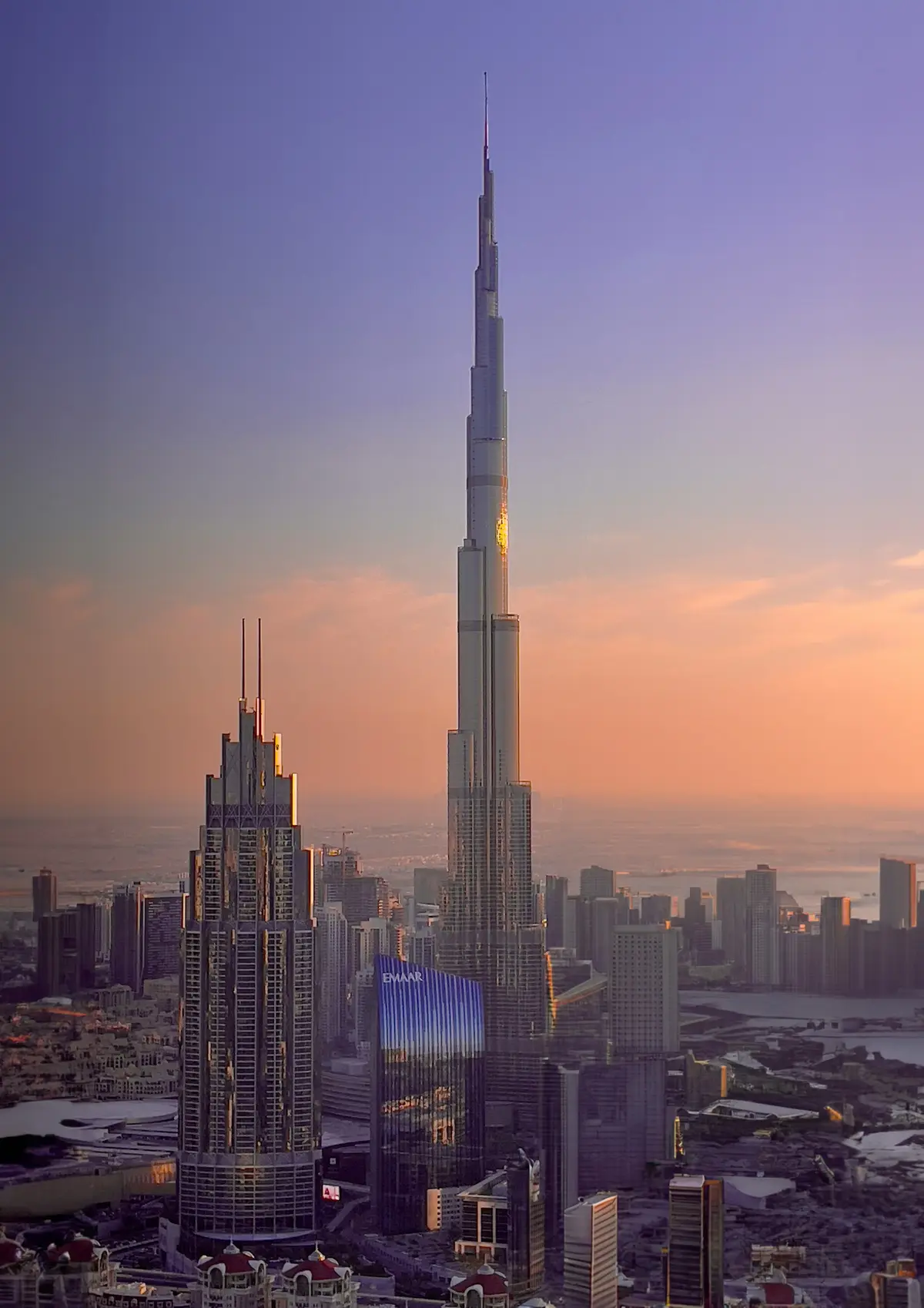 The Burj Khalifa at sunset in a violet and orange sky above the Dubai skyline