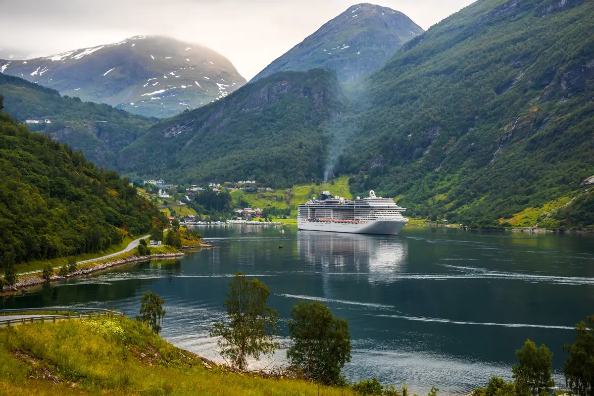 A cruise ship in the Geiranger fjord beneath snow-streaked mountains, Norway