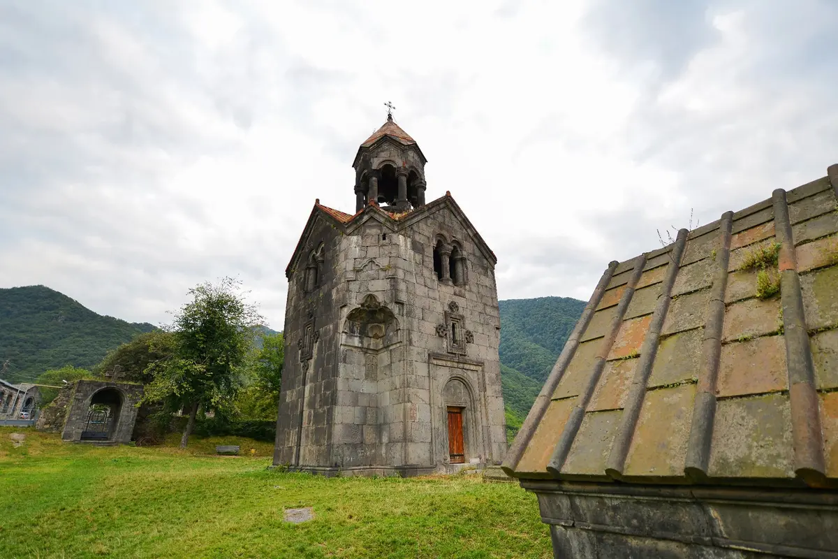 Steinerner Glockenturm des Klosters Haghpat vor grünen Bergen