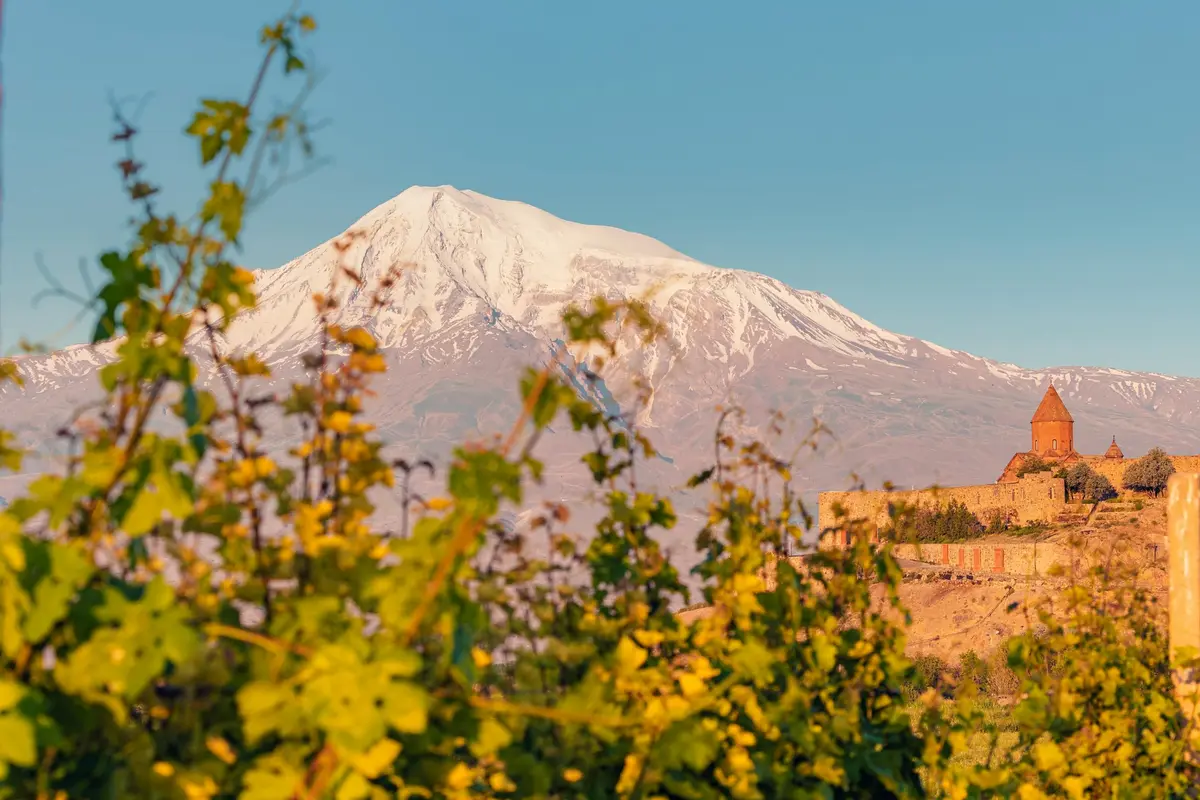Kloster Chor Virap auf einem Hügel vor dem schneebedeckten Ararat, durch goldene Weinblätter gesehen