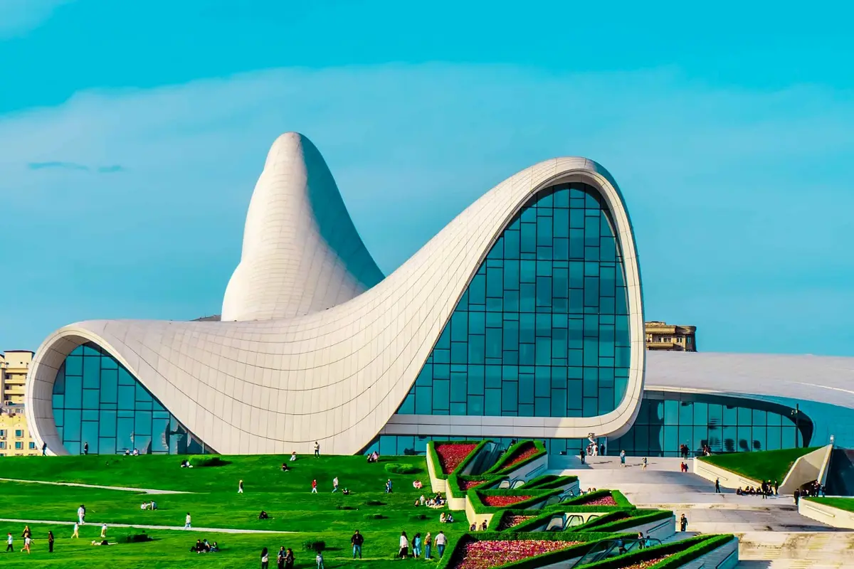 Das Heydar-Aliyev-Zentrum in Baku mit Besuchern auf dem grünen Rasen und den Blumenterrassen