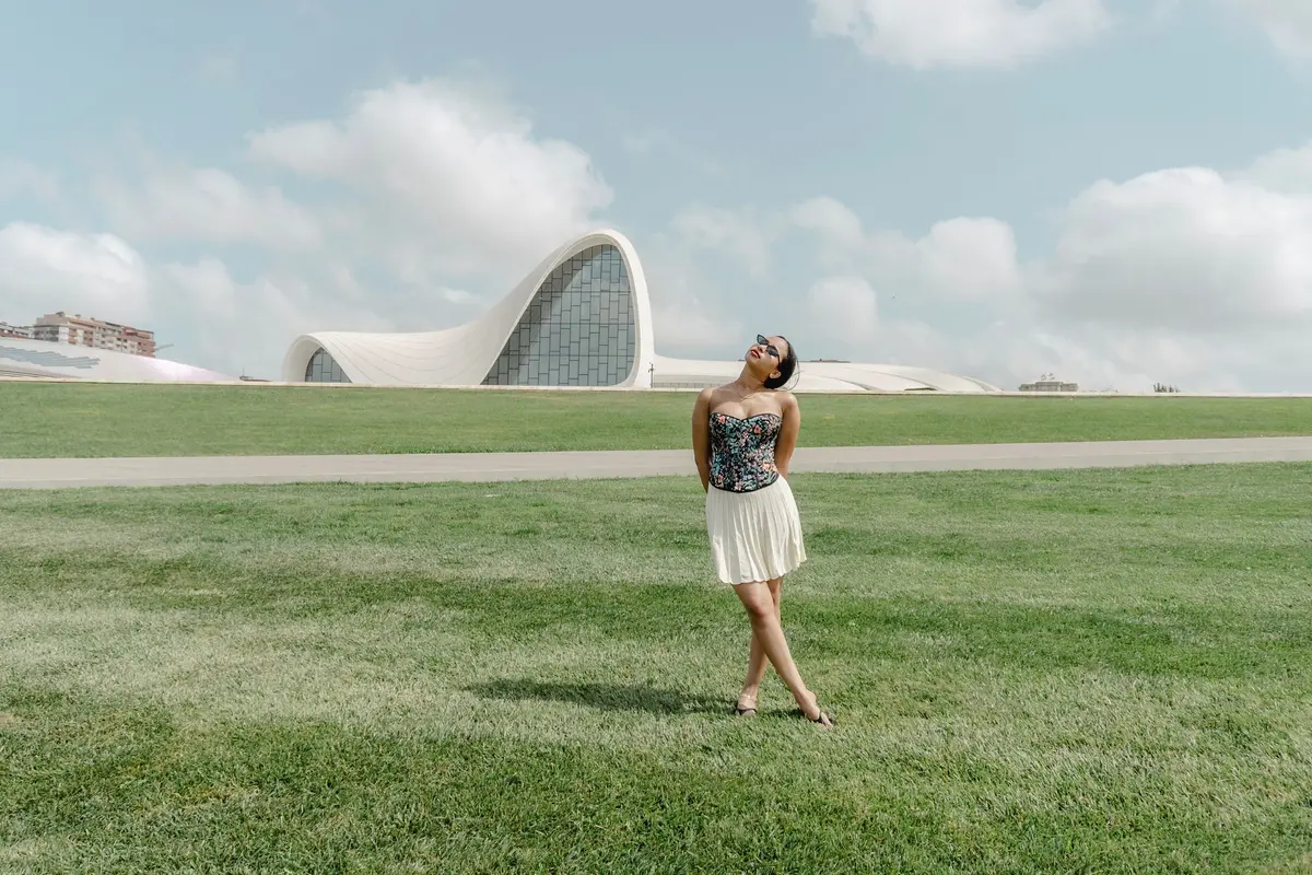 Eine Frau mit Sonnenbrille auf dem Rasen vor dem Heydar-Aliyev-Zentrum in Baku