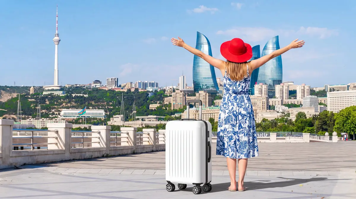 A traveller in a red hat with open arms in front of the Flame Towers in Baku, Azerbaijan (illustrative image)