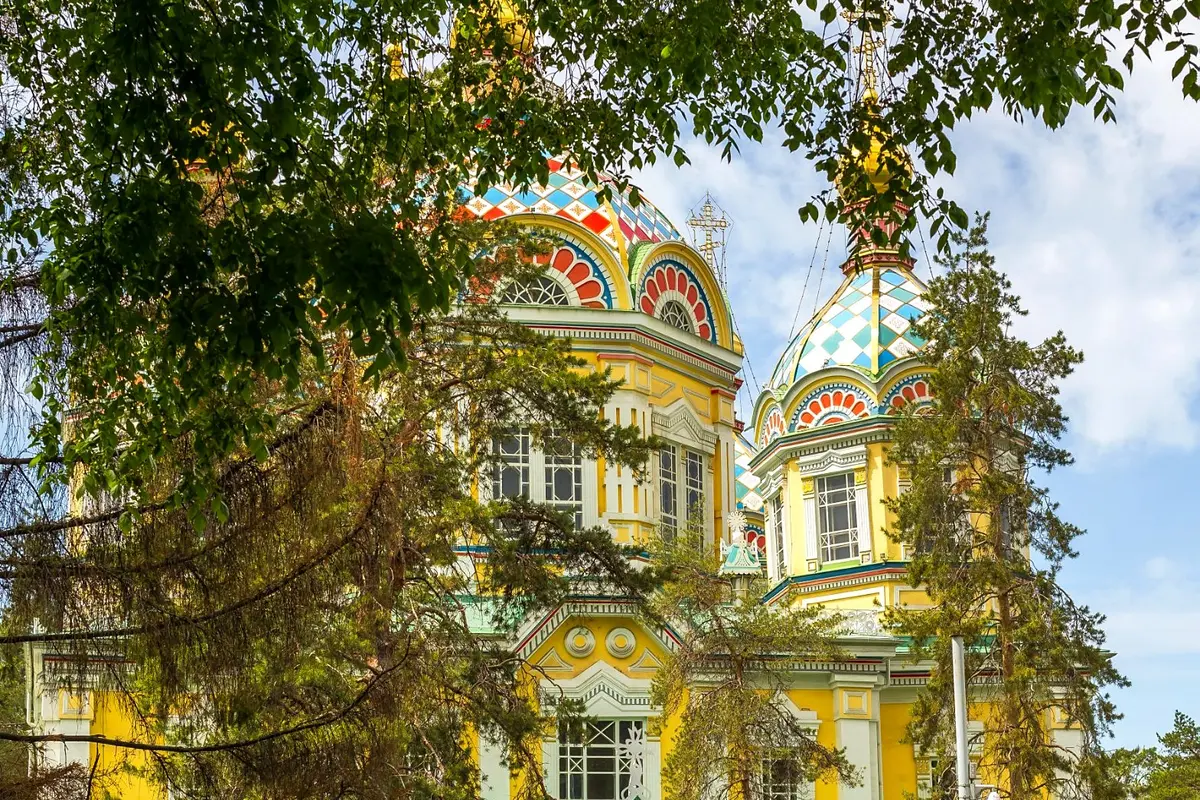Die bunte hölzerne Himmelfahrtskathedrale im Panfilow-Park von Almaty mit Frühlingstulpen