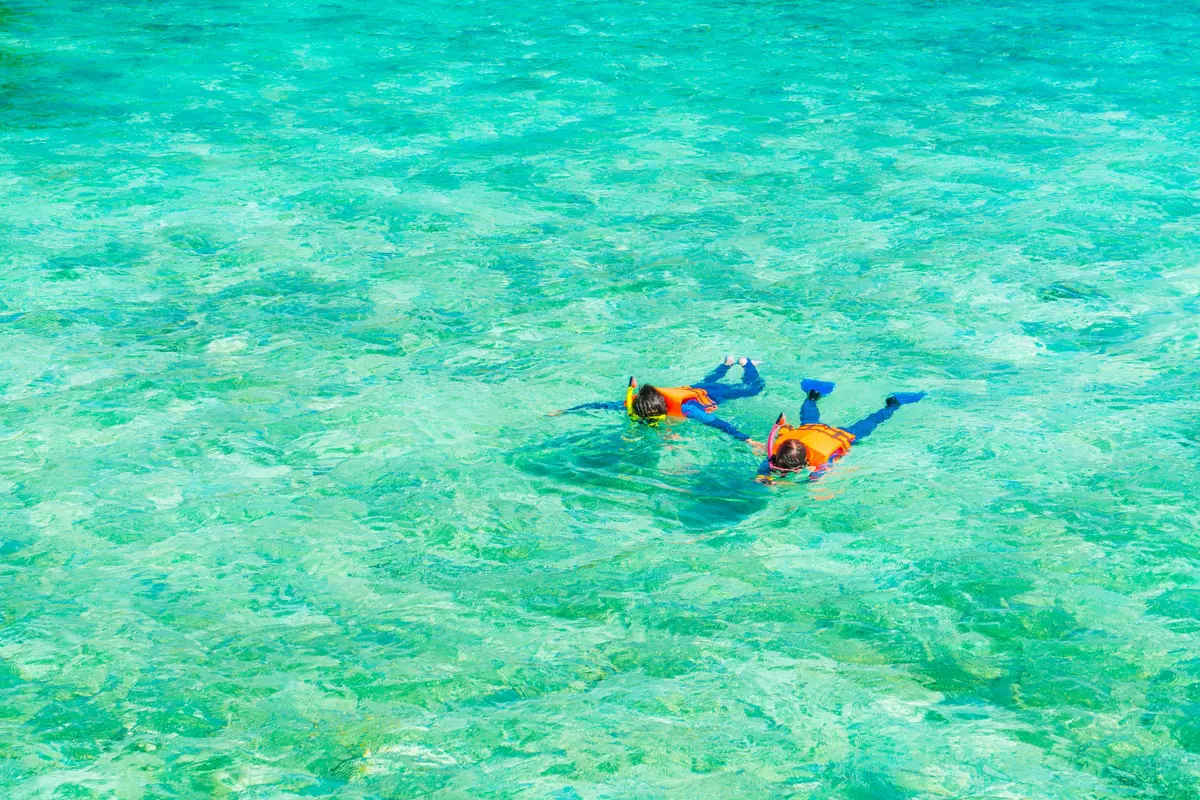 Un couple fait du snorkeling dans l’eau cristalline des Maldives