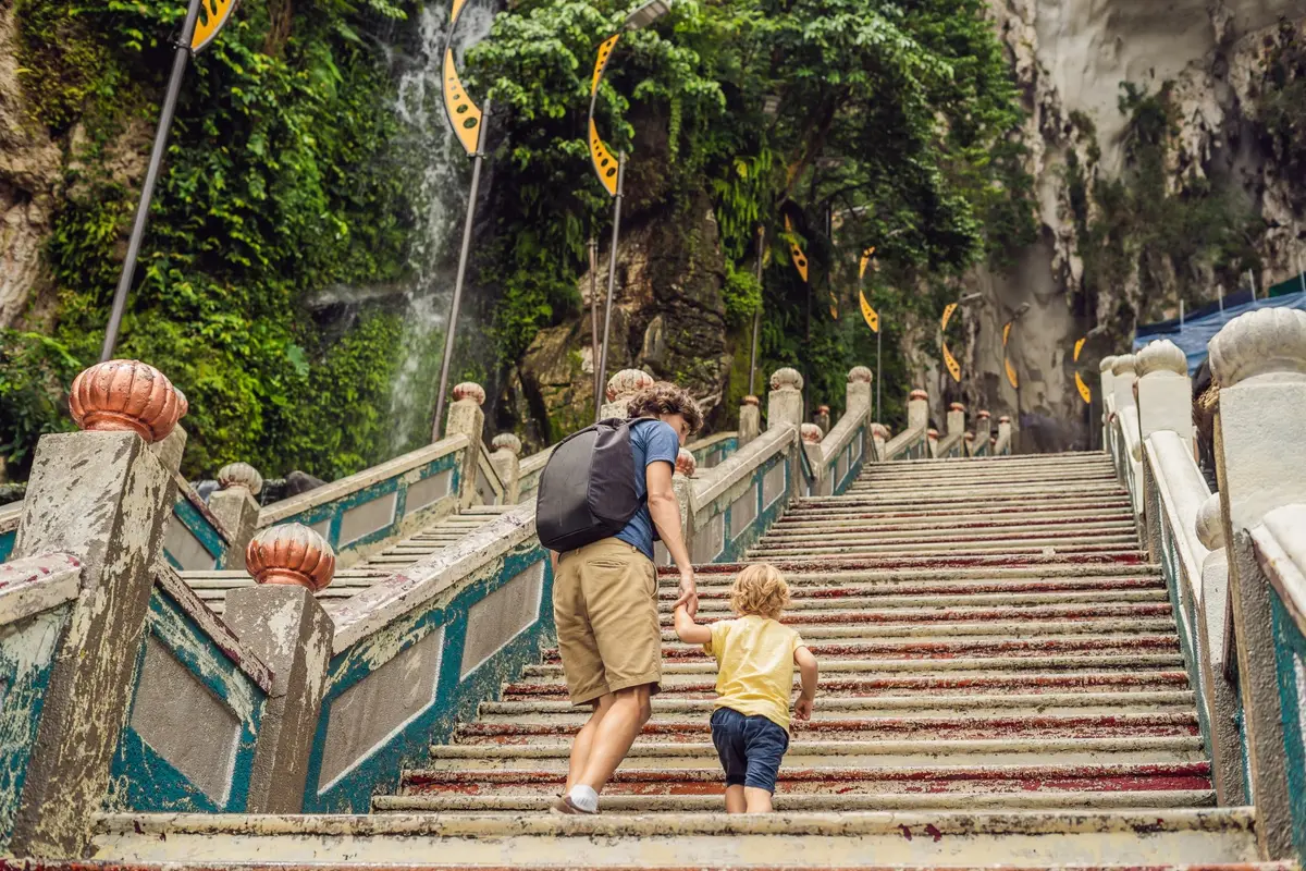 Un parent et son enfant gravissent l'escalier coloré des grottes de Batu, près de Kuala Lumpur