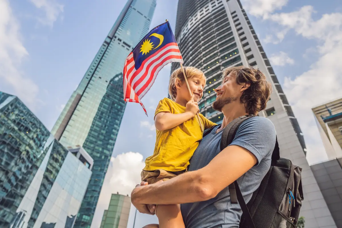 Pater filium gestat, qui vexillum Malaesiae inter caeli radentia Kuala Lumpur agitat