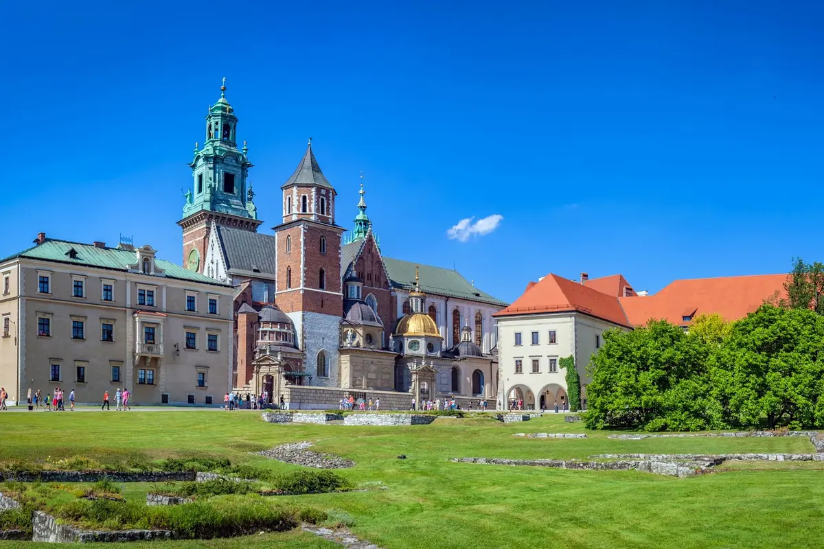 Der Wawel in Krakau: die Kathedrale mit grünen und goldenen Kuppeln und der Schlossturm unter tiefblauem Sommerhimmel