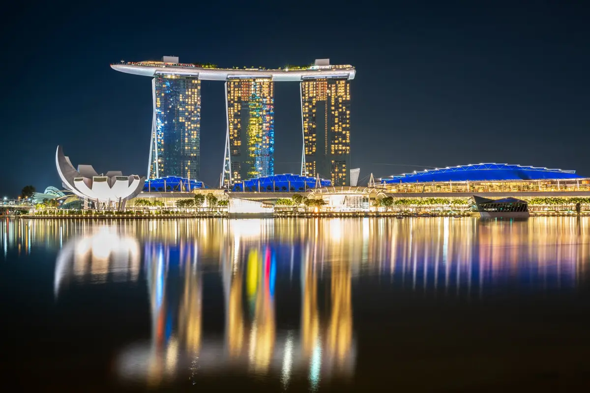Die nachts beleuchtete Skyline der Marina Bay, im Wasser gespiegelt