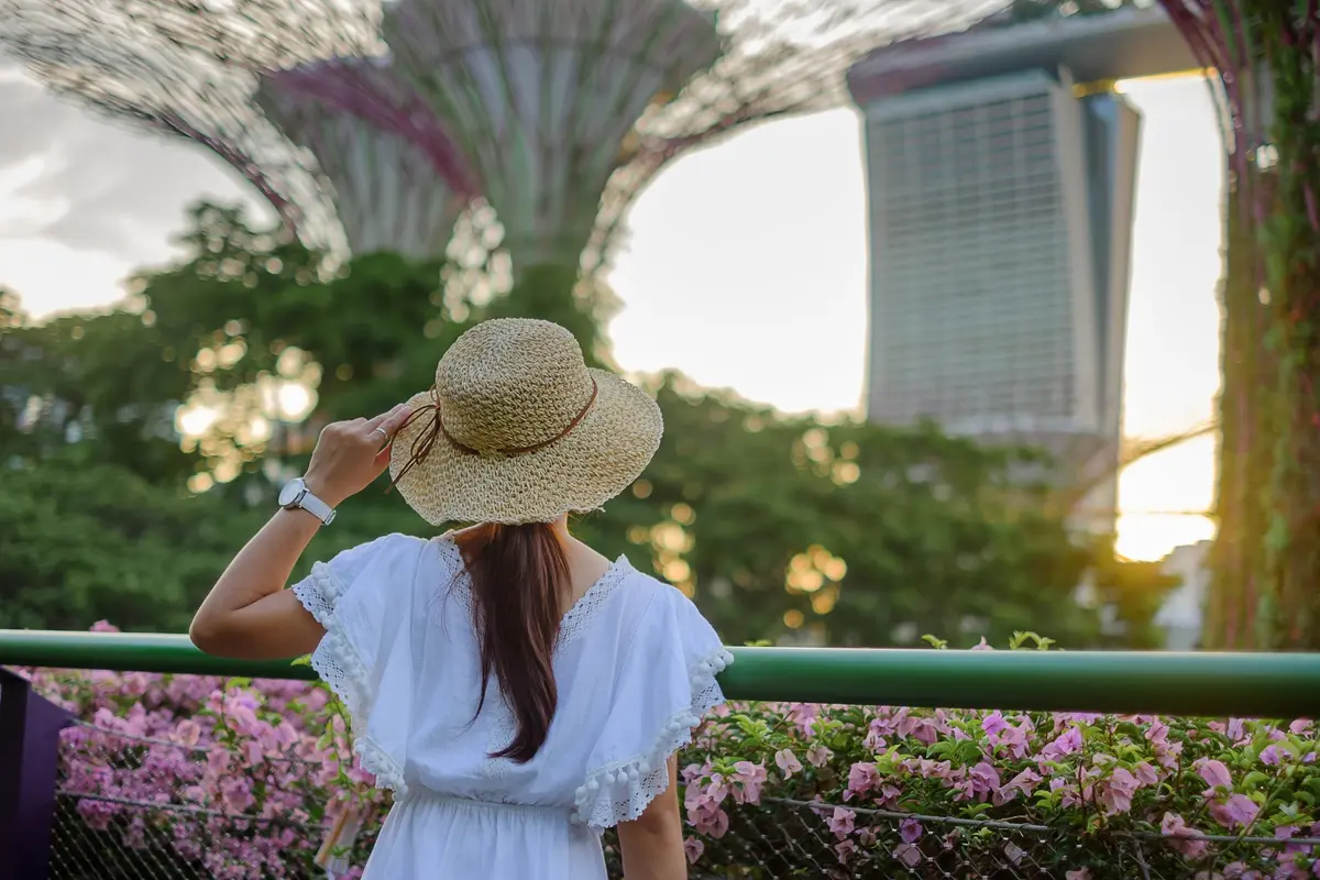 Eine Reisende mit Strohhut blickt auf die Supertrees der Gardens by the Bay