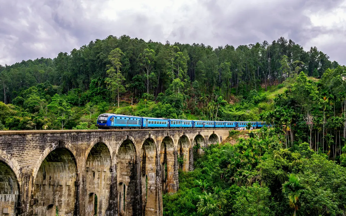 A blue train crossing the Nine Arches Bridge in Ella, Sri Lanka