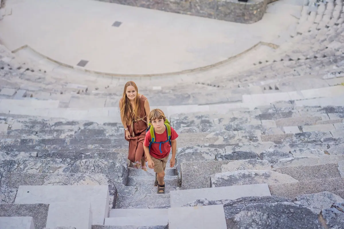 Eine Mutter und ihr Sohn steigen die Steinränge des antiken Theaters von Aspendos hinauf