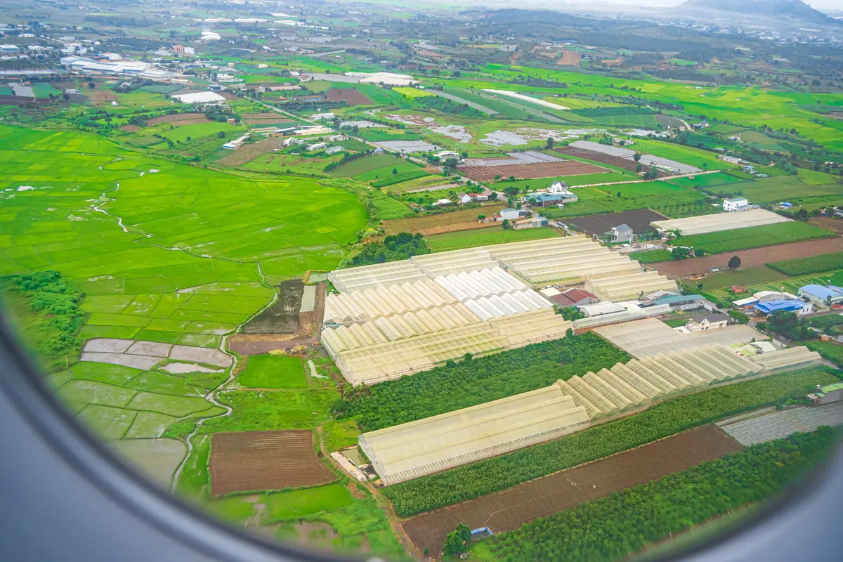 Grüne Felder und Gewächshäuser bei Dalat, vom Flugzeugfenster aus gesehen