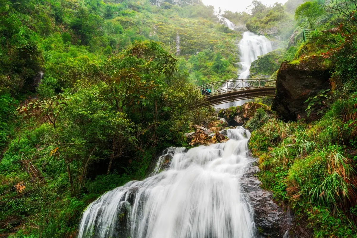 Der Silberwasserfall und eine Fußgängerbrücke darüber im Wald von Sapa
