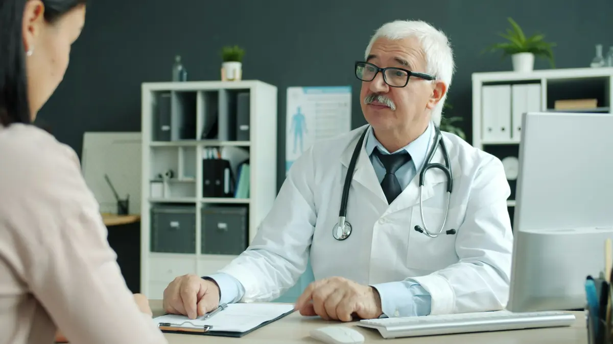 A doctor in a white coat talking with a patient in a modern office
